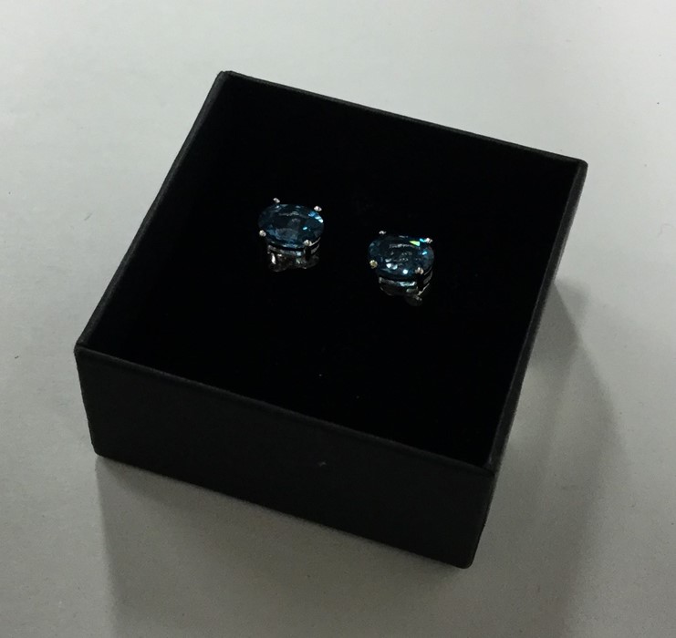A pair of blue topaz ear studs in claw mounts. Est