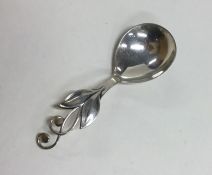 A stylish silver caddy spoon with floral decoratio