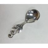 A stylish silver caddy spoon with floral decoratio