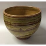 A yellow and brown glazed stoneware bowl on pedest