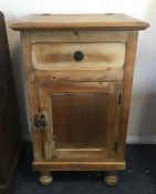 A stripped pine hinged top cupboard on four bun fe