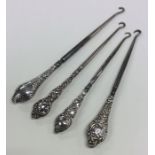 A group of four silver button hooks with embossed