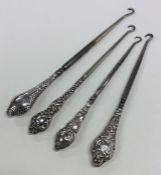 A group of four silver button hooks with embossed
