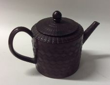 A small terracotta glazed teapot with incised wave