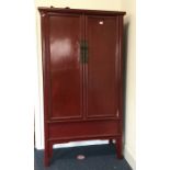 A red lacquered two door cupboard. Est. £150 - £25