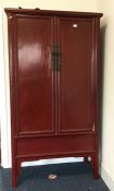 A red lacquered two door cupboard. Est. £150 - £25