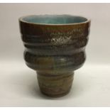 A top heavy drip glazed stoneware pottery vase on