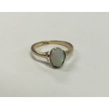 An opal single stone ring in rubover gold mount. A