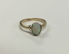 An opal single stone ring in rubover gold mount. A