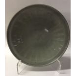 A circular shallow Chinese glazed celadon dish of