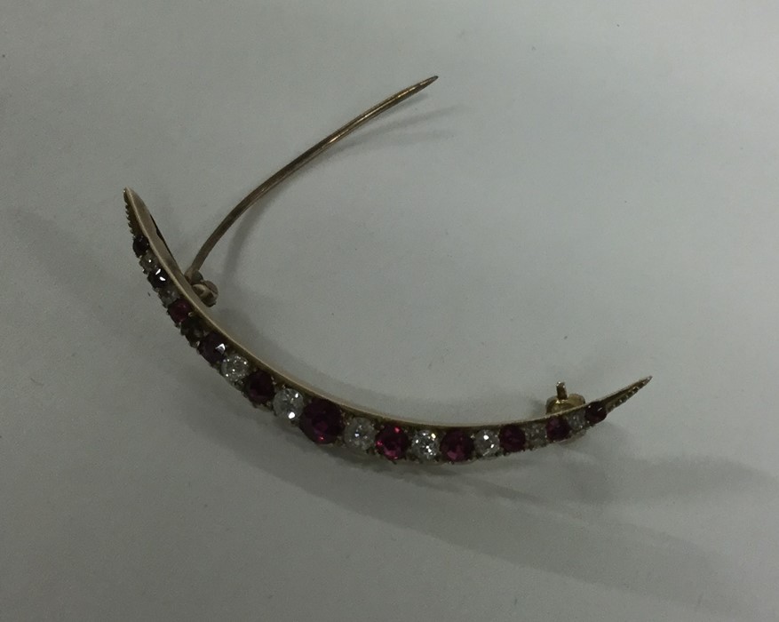 A ruby and diamond crescent brooch in gold mount.