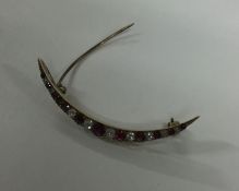A ruby and diamond crescent brooch in gold mount.
