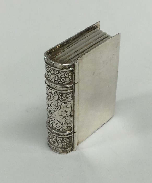 A silver pill box in the form of a book with engra