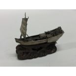 A small silver model of a junk on carved wooden st