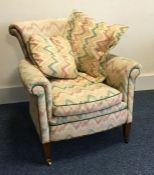 A Victorian upholstered armchair on tapering suppo