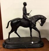 A tall bronze figure of a horse and rider on oval