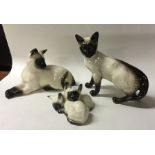 A set of three Beswick figures of Siamese cats. Es