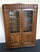 An oak two door glazed cabinet. Est. £30 - £50.