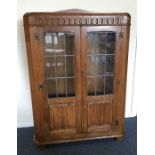 An oak two door glazed cabinet. Est. £30 - £50.