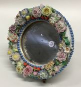 A small porcelain Barbola mirror with mahogany sta