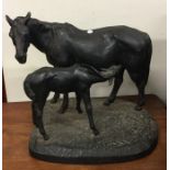 A large cast iron figure of a horse and foal on ru