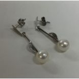 A pair of pearl and diamond drop earrings set in w