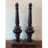 A pair of turned wooden candlesticks on square bas