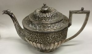 A heavy Indian silver teapot decorated with flower