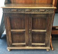 An oak two door cupboard on bun feet. Est. £20 - £