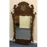 A gilt and mahogany wall mirror. Est. £30 - £50.