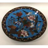 A circular cloisonné wall plate decorated with bri