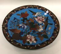 A circular cloisonné wall plate decorated with bri