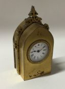 A small brass travelling clock of Gothic design wi