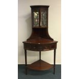 An Edwardian mahogany corner cabinet with bevelled