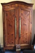 A large fruit wood armoire with shaped top and bra