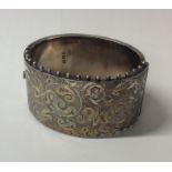 A Victorian silver hinged bangle with scroll decor