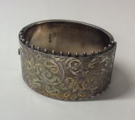 A Victorian silver hinged bangle with scroll decor