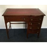 An Edwardian mahogany kidney shaped desk with cros