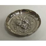 A small silver chased dish decorated with fruit in