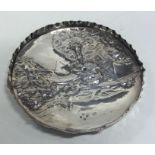 A circular chased silver dish with cottage scene.