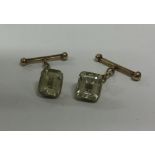 A pair of gold and green stone cufflinks on suspen
