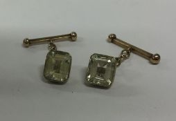 A pair of gold and green stone cufflinks on suspen