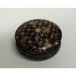 A circular tortoiseshell and gold inlaid box with