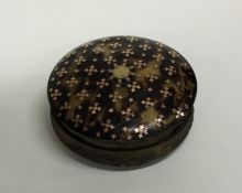 A circular tortoiseshell and gold inlaid box with