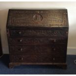 A large heavily carved oak fall front bureau with