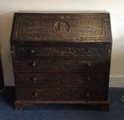 A large heavily carved oak fall front bureau with