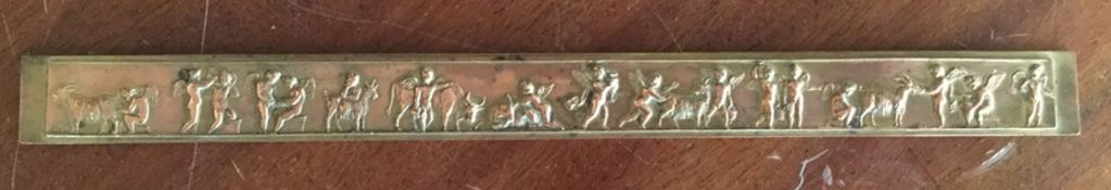 A long brass ruler depicting winged infants. Appro
