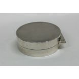 A circular silver hinged top pill box with flush f