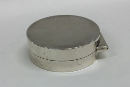 A circular silver hinged top pill box with flush f
