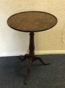 An Antique circular oak pedestal table on three sw